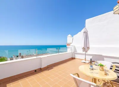 a balcony with a table and chairs and the ocean at Apartamentos El Roqueo in Conil de la Frontera