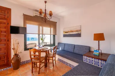 a living room with a blue couch and a table at Apartamentos El Roqueo in Conil de la Frontera