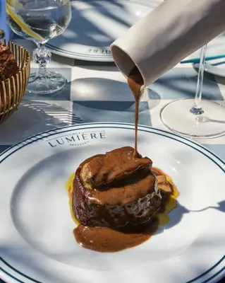a person drizzling sauce onto a dessert on a plate at Royal Hideaway Sancti Petri in Chiclana de la Frontera