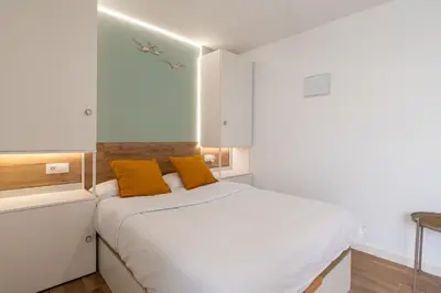 a bedroom with a white bed with two orange pillows at Azotea Rooftop Playa la Caleta in Cádiz