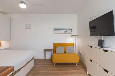 a bedroom with a bed and a yellow chair at Azotea Rooftop Playa la Caleta in Cádiz