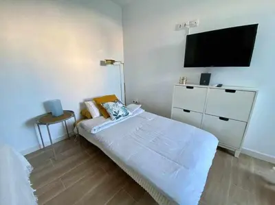 a bedroom with a bed and a flat screen tv at Azotea Rooftop Playa la Caleta in Cádiz