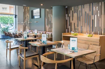 a restaurant with wooden tables and chairs and a bar at Occidental Cádiz in Cádiz