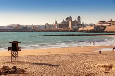 a beach with a lifeguard tower on the beach at Occidental Cádiz in Cádiz
