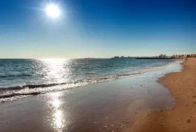 a beach with the sun reflecting on the water at Occidental Cádiz in Cádiz