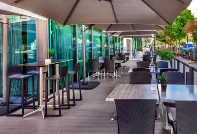 an outdoor restaurant with tables and chairs and umbrellas at Occidental Cádiz in Cádiz