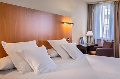 a hotel room with a bed with white pillows at Occidental Cádiz in Cádiz