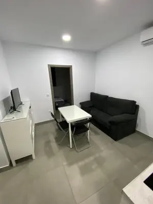 a living room with a black couch and a table at APARTAMENTOS PASCUAL in El Cuervo