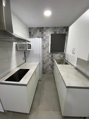a kitchen with white counters and a white refrigerator at APARTAMENTOS PASCUAL in El Cuervo