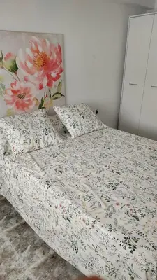 a bed with a floral comforter and pillows on it at PISABEL in Sanlúcar de Barrameda
