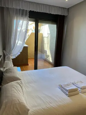 a bedroom with a white bed with towels on it at Ático primera línea de playa. in Cádiz