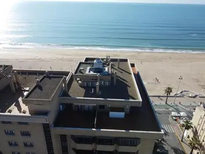 an aerial view of a building and the beach at Ático primera línea de playa. in Cádiz