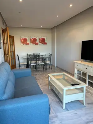 a living room with a blue couch and a table at Ático primera línea de playa. in Cádiz