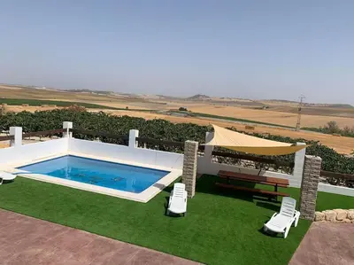 a pool with two chairs and a table and a umbrella at Santa Lucía in Jerez de la Frontera