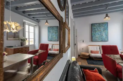 a living room with a mirror and red chairs at Apartamento Sweet Home in Cádiz in Cádiz