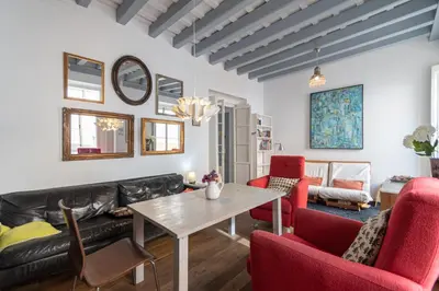 a living room with a black leather couch and red chairs at Apartamento Sweet Home in Cádiz in Cádiz