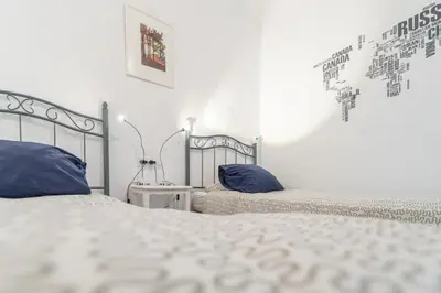 a white bedroom with two beds with blue pillows at Apartamento Sweet Home in Cádiz in Cádiz