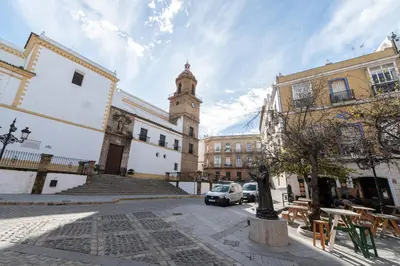 a building with a clock tower in the middle of a street at Apartamento El Bergantin de Cádiz in Cádiz