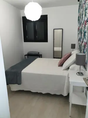 a bedroom with a large white bed and a mirror at LHOME CÁDIZ in Cádiz