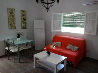 a living room with a red couch and a table at Casa tranquila , muy bien ubicada in Chiclana de la Frontera