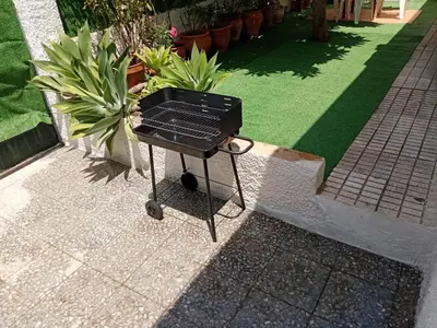 a grill sitting on the ground next to some plants at Casa tranquila , muy bien ubicada in Chiclana de la Frontera