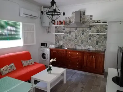 a living room with a red couch and a kitchen at Casa tranquila , muy bien ubicada in Chiclana de la Frontera
