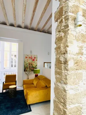 a living room with a yellow couch and a stone wall at inncadizcasa Señorial de Rivadavia in Cádiz