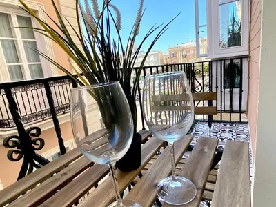 two wine glasses sitting on a bench on a balcony at inncadizcasa Señorial de Rivadavia in Cádiz
