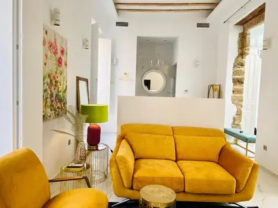 a living room with a yellow couch and a mirror at inncadizcasa Señorial de Rivadavia in Cádiz