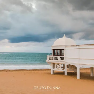 a white building on a beach with the ocean at Apartamentos La Tahona Cádiz Centro in Cádiz