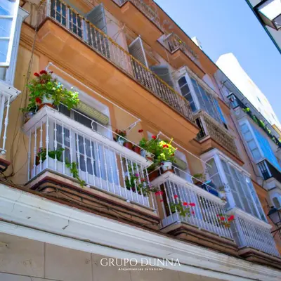 a building with windows and balconies with flowers on them at Apartamentos La Tahona Cádiz Centro in Cádiz