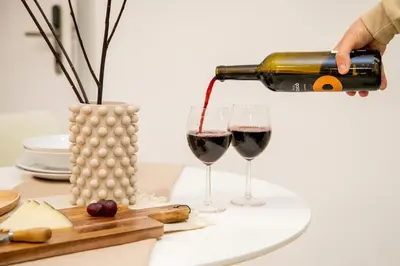 a person pouring wine into two glasses on a table at Apartamentos La Tahona Cádiz Centro in Cádiz