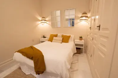a bedroom with a white bed with yellow pillows at inncadizCasa Apolo in Cádiz