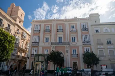 a large pink building with people standing in front of it at inncadizCasa Apolo in Cádiz