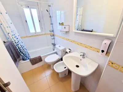 a white bathroom with a toilet and a sink at Apartamento Alférez in Sanlúcar de Barrameda