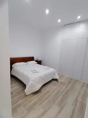 a white bedroom with a bed and a wooden floor at Sol Alameda Grupo AC Gestion in Cádiz