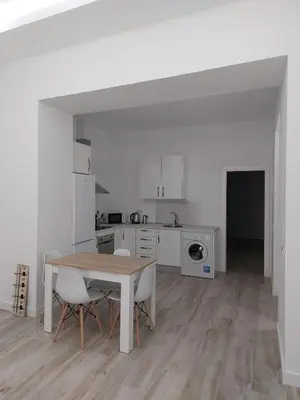 a white kitchen with a table and chairs in it at Sol Alameda Grupo AC Gestion in Cádiz