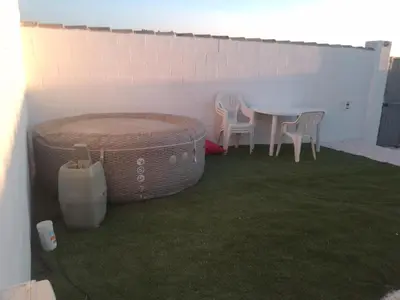 a patio with a table and chairs on the grass at Tiny house Chill escape para 7 - private Jacussy Brisa & Burbujas in Chiclana de la Frontera