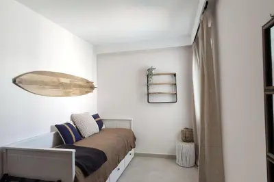 a bedroom with white walls and a bed and a window at Piso reformado de diseño c/terraza. Playa el Ancla in El Puerto de Santa María