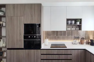 a kitchen with a black microwave and wooden cabinets at Piso reformado de diseño c/terraza. Playa el Ancla in El Puerto de Santa María