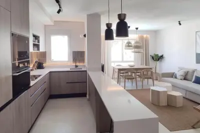 a kitchen and living room with a couch and a table at Piso reformado de diseño c/terraza. Playa el Ancla in El Puerto de Santa María