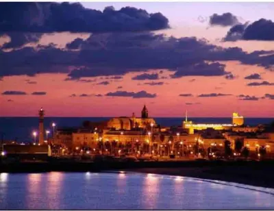 a city lit up at night with the water at Viento Grande, Apartamento boutique en la playa in Rota
