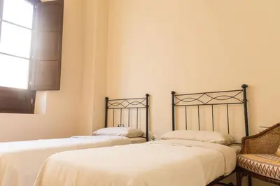 a room with two beds and a chair and a window at Candié by Gades Gestión in Cádiz