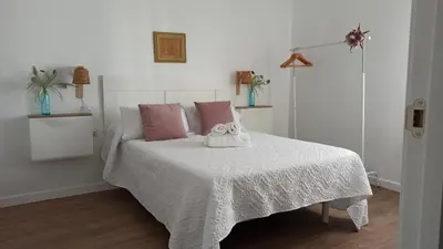 a bedroom with a white bed with pink pillows at Acogedor piso centro, San Miguel in Jerez de la Frontera
