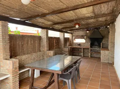 an outdoor kitchen with a wooden table and chairs at Gran Casa con Piscina Privada by Chiclana Dreams in Chiclana de la Frontera