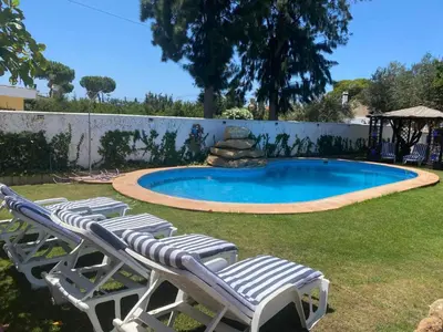 a group of lawn chairs and a swimming pool at Gran Casa con Piscina Privada by Chiclana Dreams in Chiclana de la Frontera