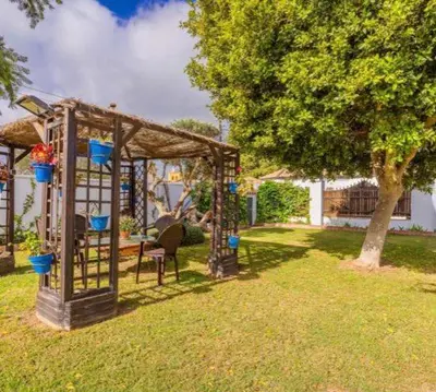 a gazebo with a table and a chair in a yard at Gran Casa con Piscina Privada by Chiclana Dreams in Chiclana de la Frontera