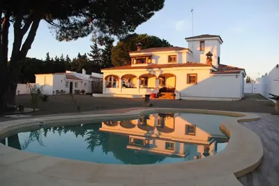 a large yellow house with a reflection in a pool at CÁDIZ - BUDA, acogedor apartamento en Chiclana de la Frontera, España in Chiclana de la Frontera