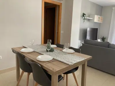 a wooden table with plates and wine glasses on it at APARTAMENTO LOS ALTOS DE EL PUERTO - Calidad, Garaje y WiFi in El Puerto de Santa María
