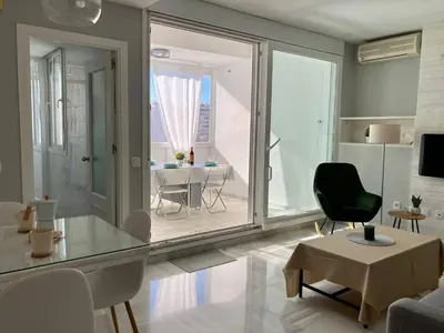 a living room with a glass table and a chair at ÁTICO VALDELAGRANA PLAYA - Aire Acondicionado y Piscina in El Puerto de Santa María